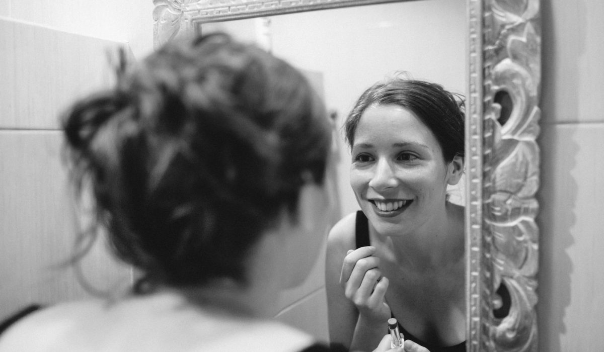 woman smiles in front of mirror